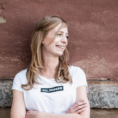 Hier ist Marnie zu sehen. Sie trägt ein weißes Shirt und schaut verträumt nach rechts.
